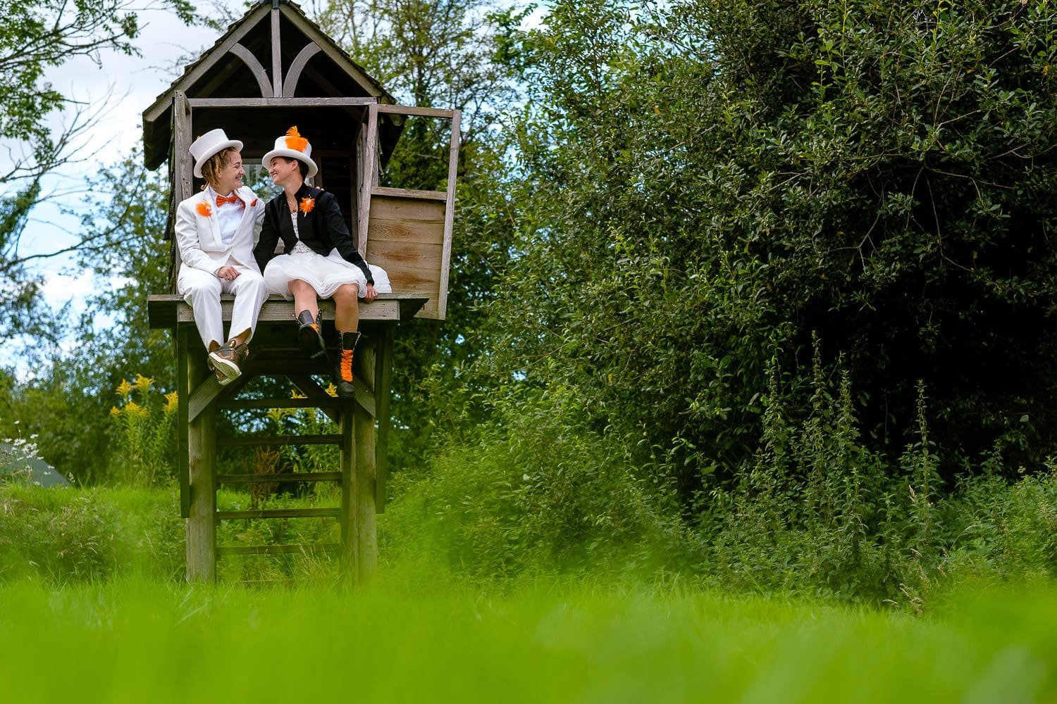 lesbian couple sitting in a treehouse after their wedding