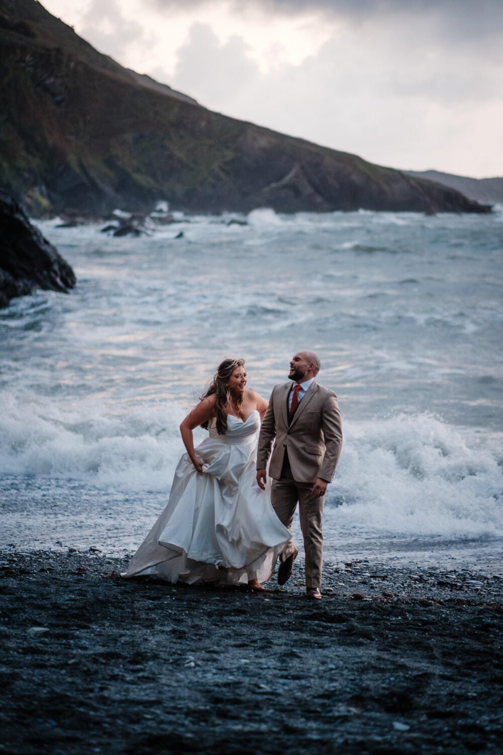 bride and groom laughing on the beach at tunnels beaches in ilfracombe